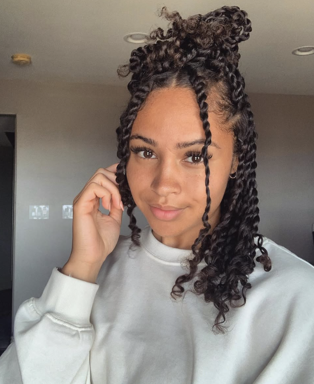 A woman with a square face shape wearing voluminous passion twists with curly ends in a half-up style, showing how the texture creates a soft frame for the jawline.