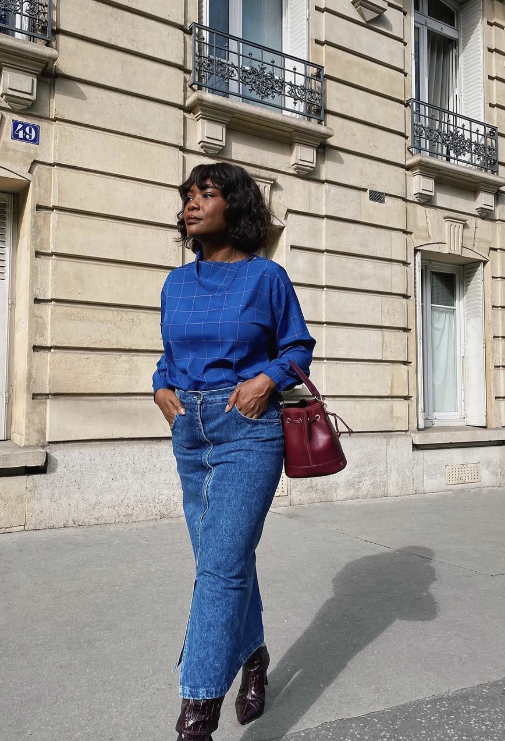 Woman wearing a straight denim midi skirt with a cobalt blue top and burgundy croc boots