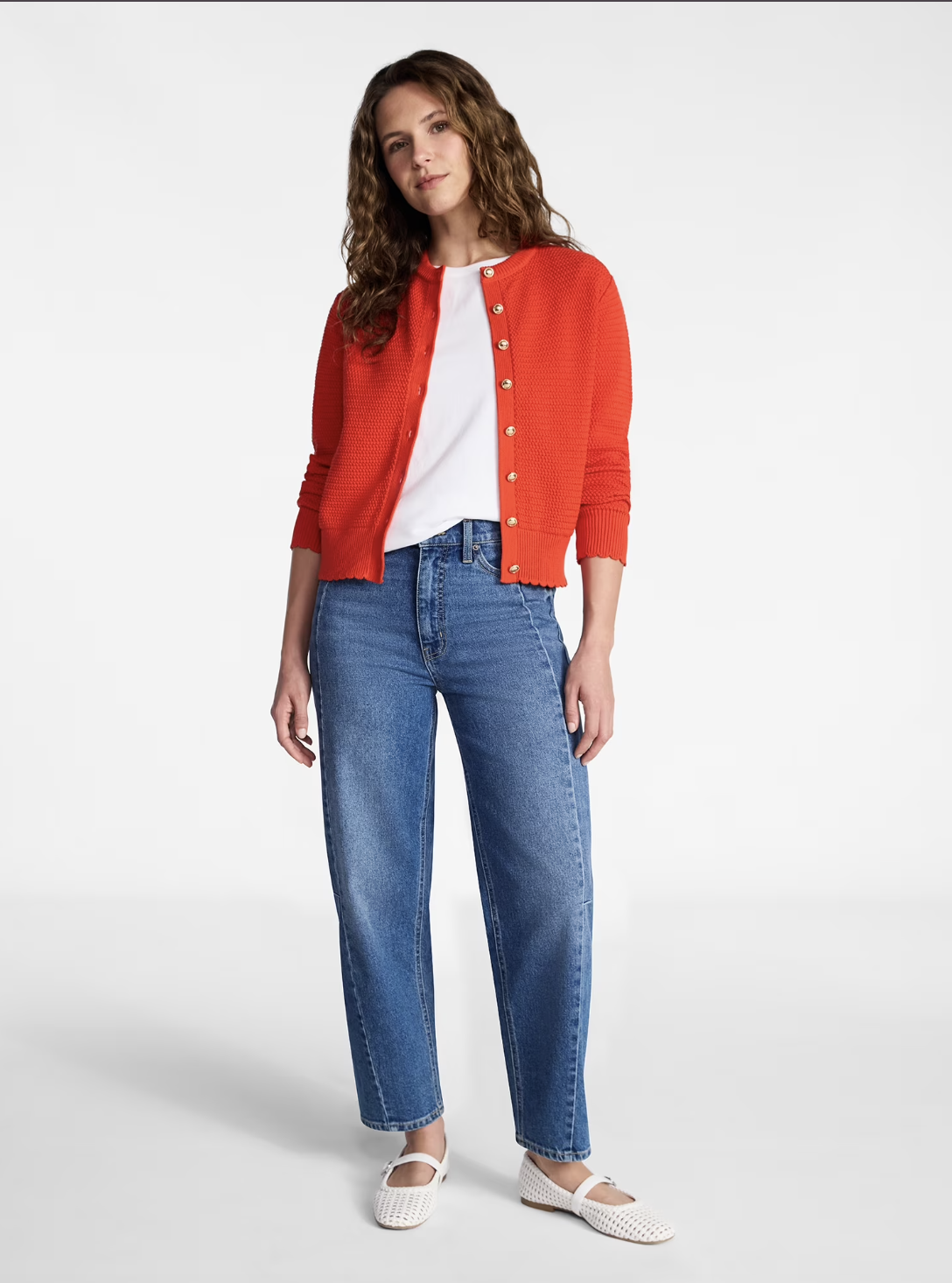 A person wearing a vibrant red-orange textured knit cardigan over a white t-shirt and classic blue straight-leg jeans, showcasing a bright and casual everyday outfit.
