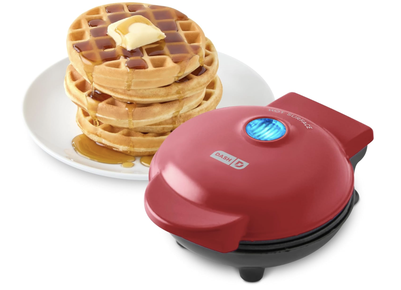 Dash Mini Waffle Maker in red shown next to a stack of warm waffles topped with butter and maple syrup set against a white background.