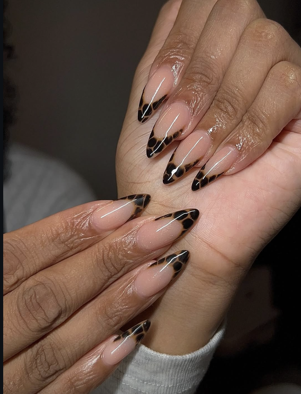 Long almond shaped nails with a nude base and translucent tortoise shell patterned French tips.