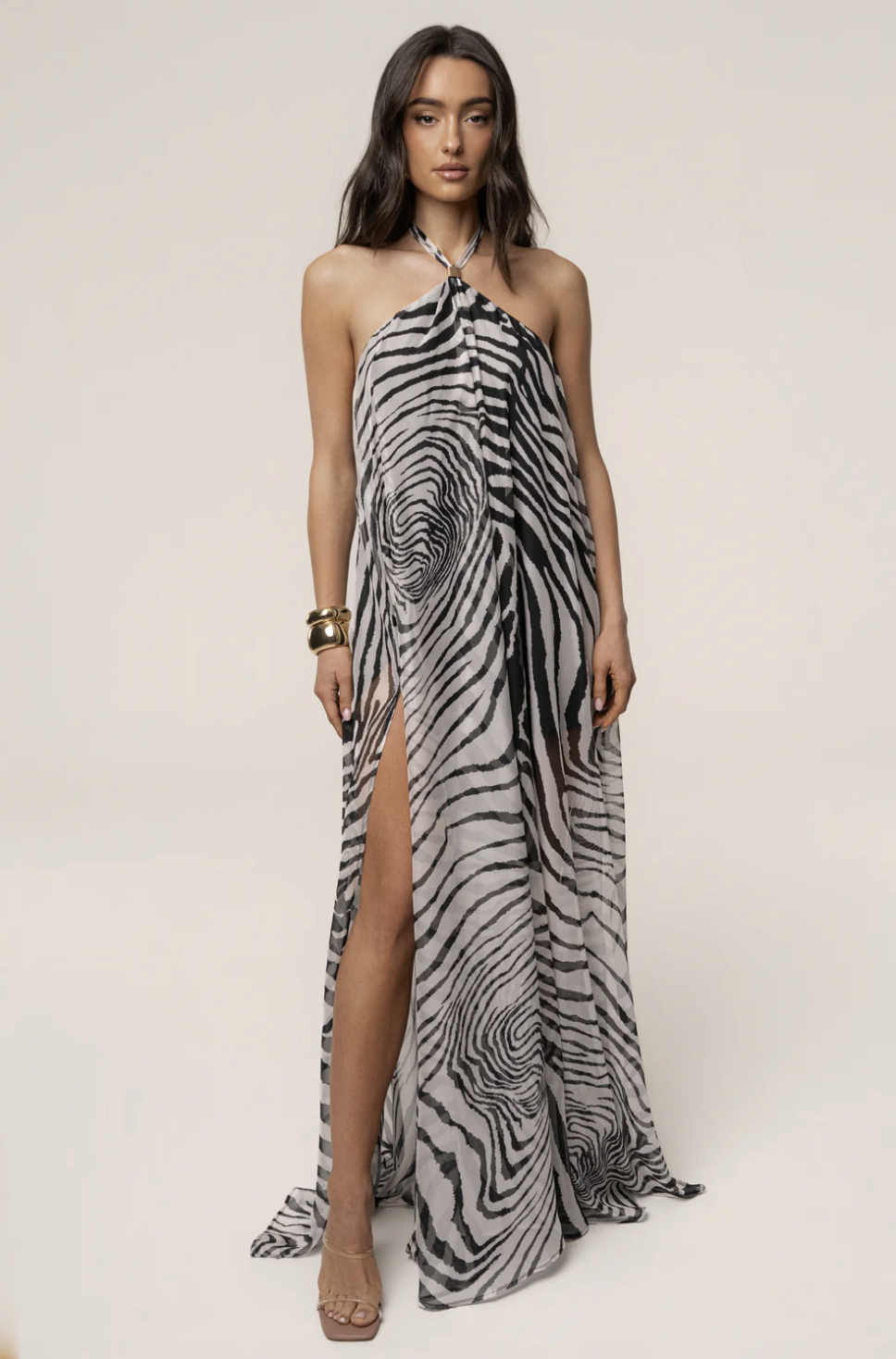 The JLUXLABEL Zebra Print Jolene Halter Dress featuring a gold-toned neck ring and high side slit, styled for a luxury Mediterranean resort look.