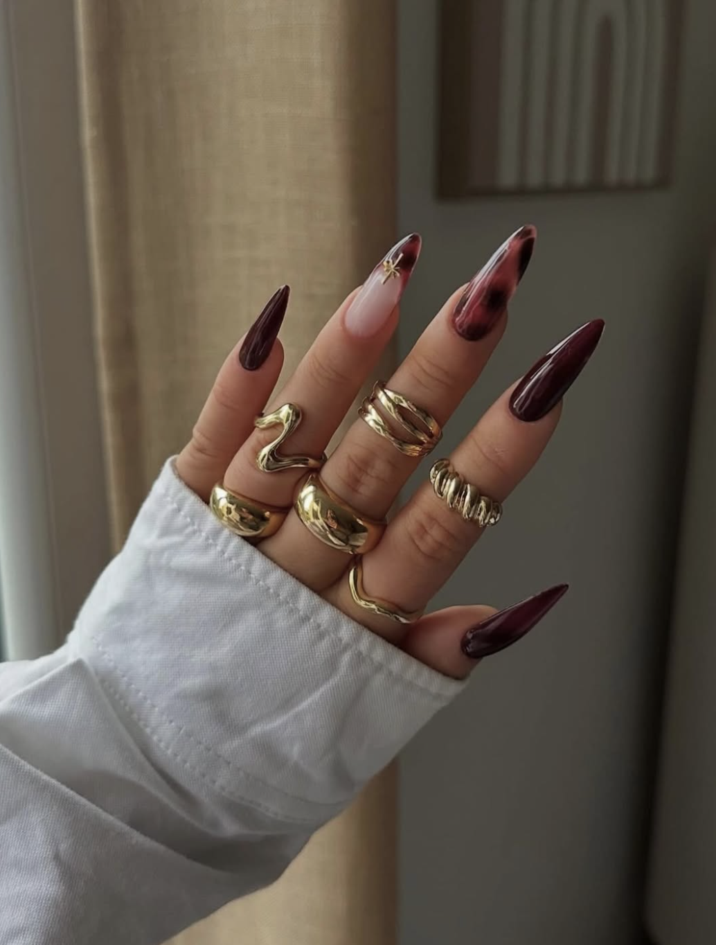 Glossy black-cherry burgundy nails in a short oval shape for autumn.