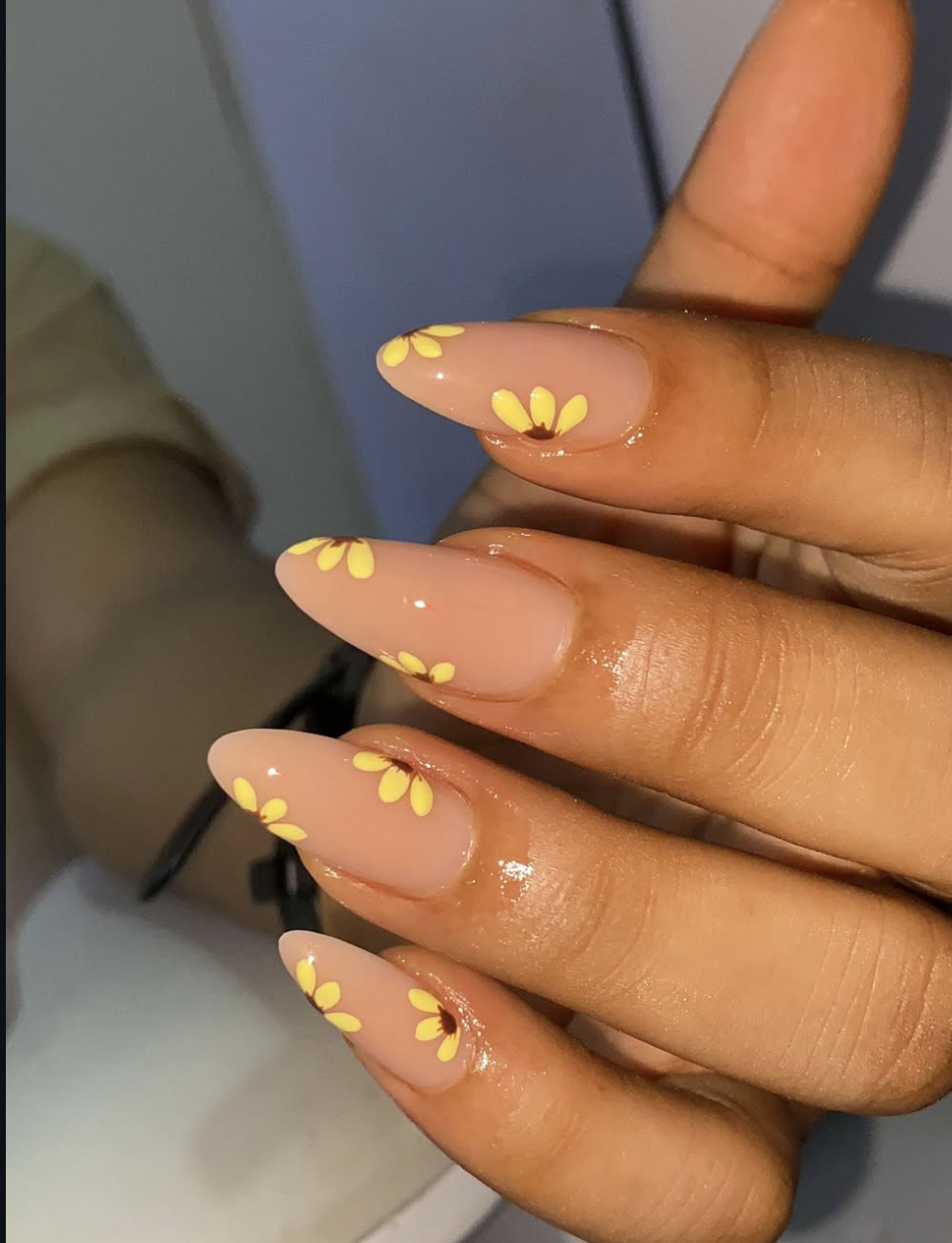 Close-up of 3D sunflower nail art on almond-shaped nails, featuring raised yellow petals and textured brown centers with small gold bead accents.