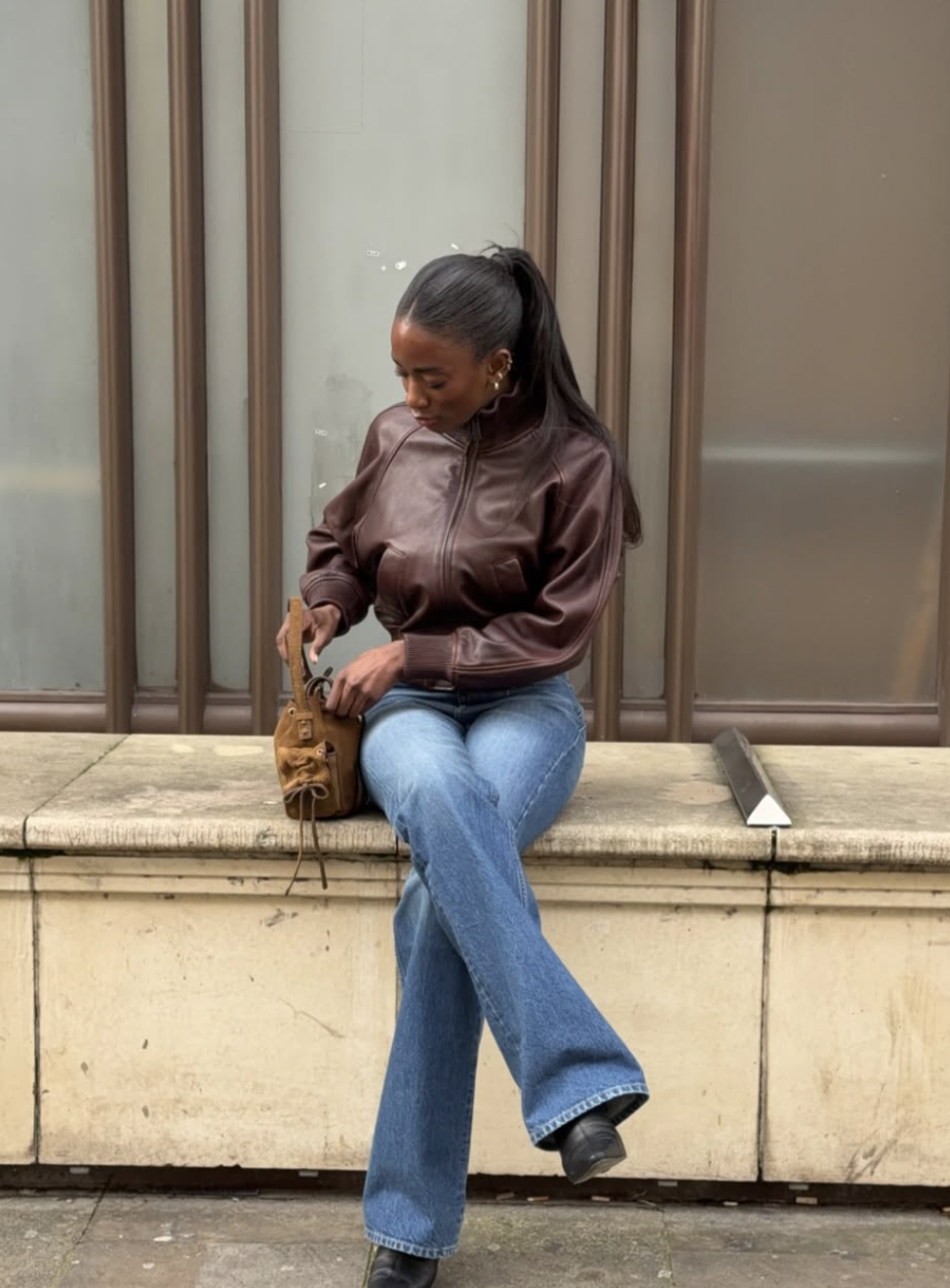 Liv Madeline styling an outfit for a long torso and short legs featuring super high-rise Levi's Ribcage jeans and a cropped brown leather bomber jacket to create balanced proportions.