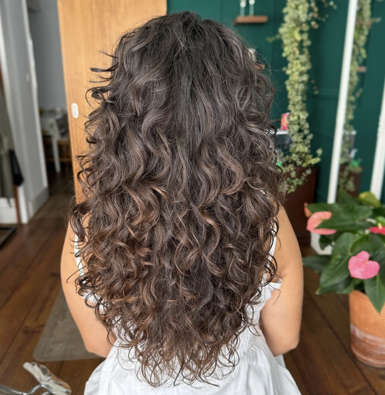 Back view of long, naturally wavy dark hair cut in a layered butterfly haircut with defined texture.