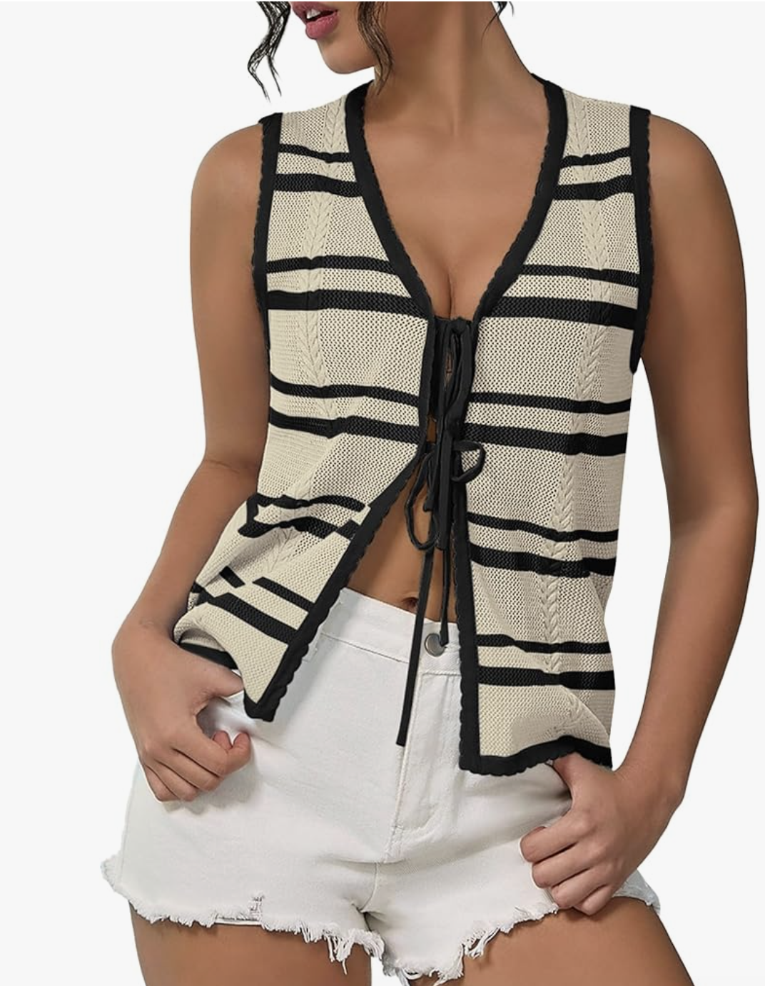 A woman wearing a black and white striped tie-front vest with white frayed denim shorts, styled as a chic daytime look for a cruise.