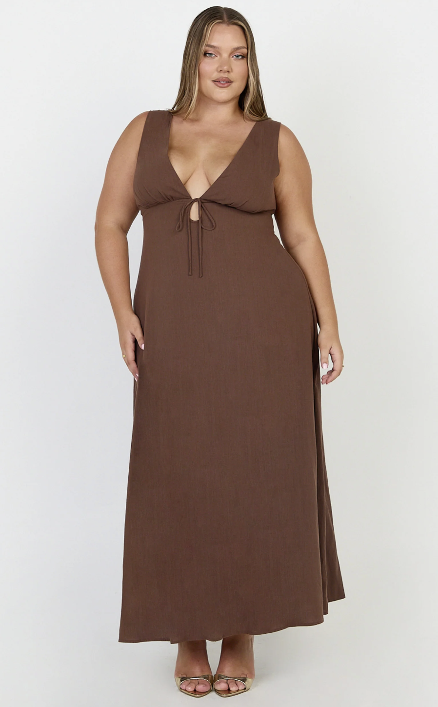 Plus-size woman wearing a brown maxi dress with a plunging neckline and tie detail.