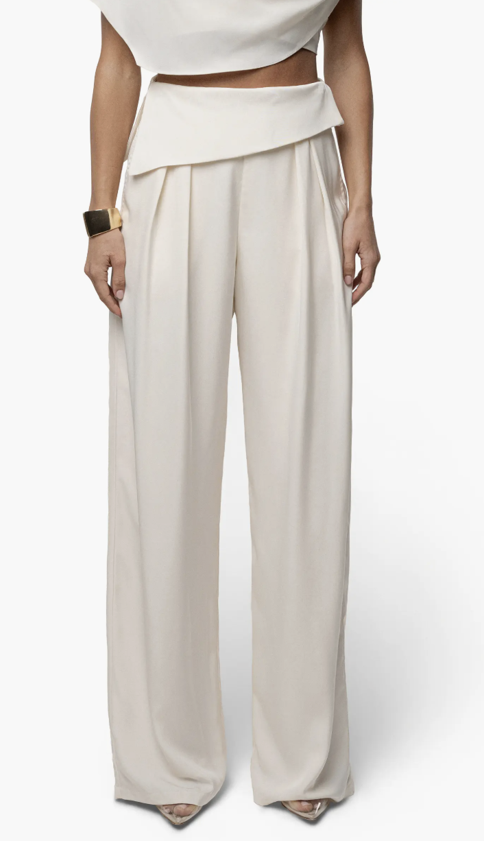 A close-up view of a woman wearing the JLUXLABEL Executive High Waist Pants in a cream color, featuring a wide-leg silhouette and tailored waist.
