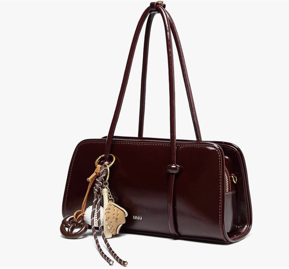 A studio product shot of a deep burgundy faux leather shoulder bag featuring a sleek rectangular shape and multiple decorative bag charms attached to the strap.