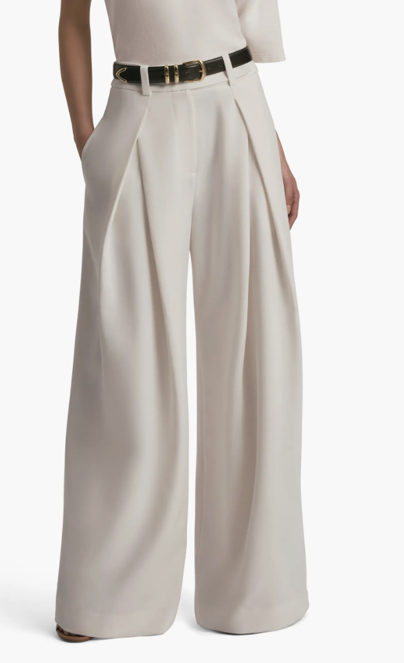 A model wearing high-waisted beige wide-leg tailored trousers styled with a dark thin belt and brown heels.