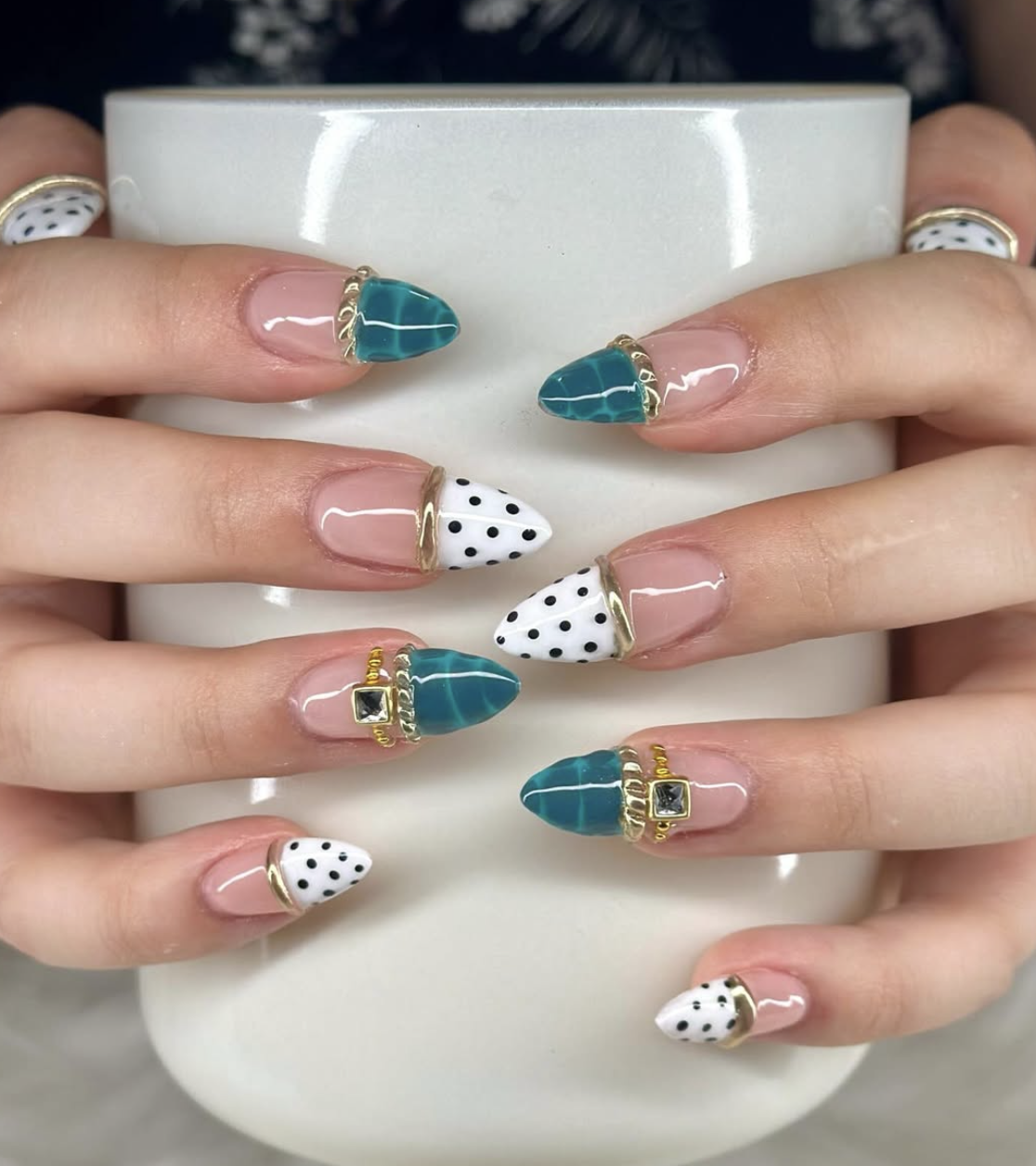 Almond-shaped nails with teal crocodile texture, white polka dots, and 3D gold bangle bands with a green gemstone charm.