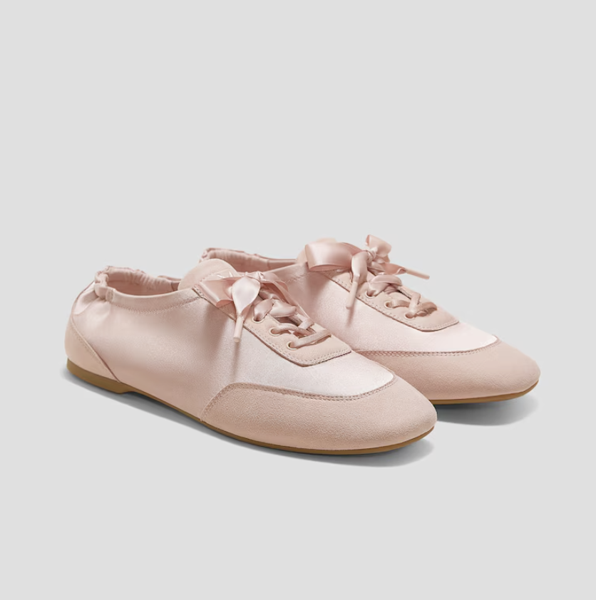 A pair of blush pink satin Sneakerina flats by Vivaia, featuring a square toe design and elegant ribbon lace-up ties, shown against a neutral background.