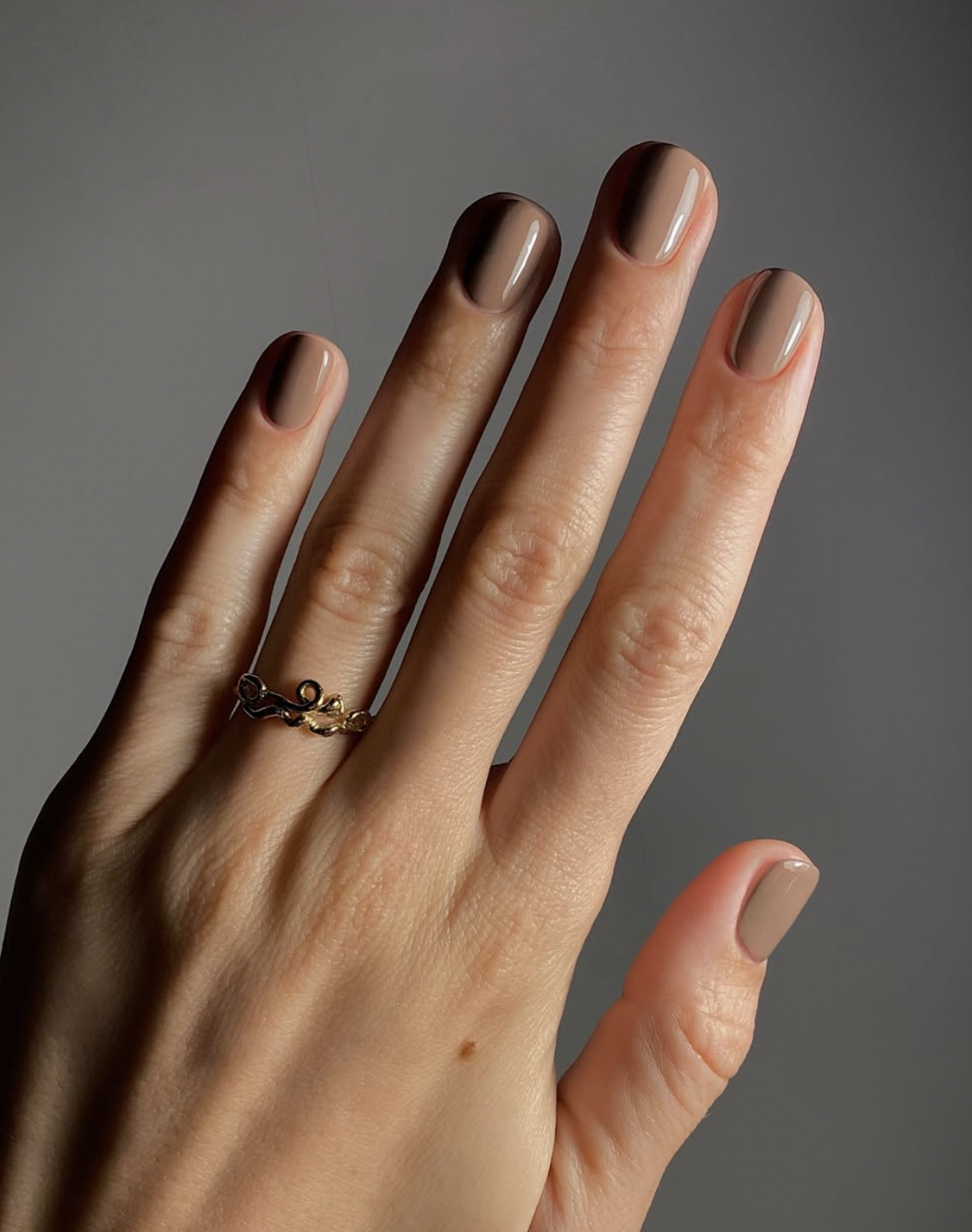 glossy caramel nude almond nails manicure photographed close up on hands.