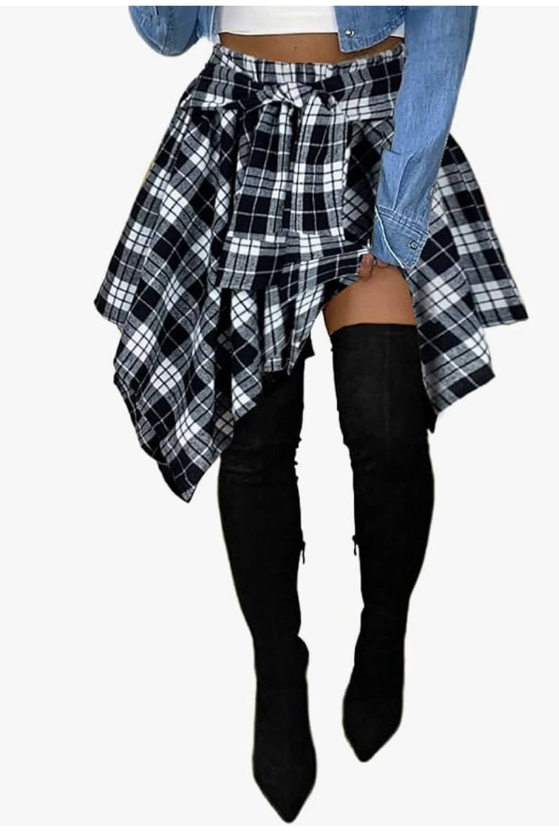 A woman wearing black pointed-toe over-the-knee suede boots styled with a blue and white plaid shirt tied around her waist.