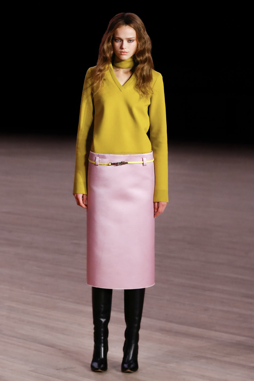 A model on the Marc Jacobs Fall/Winter 2026 runway wearing an oversized mustard yellow top and bright pink skirt, demonstrating the bold color-blocking styling trend.