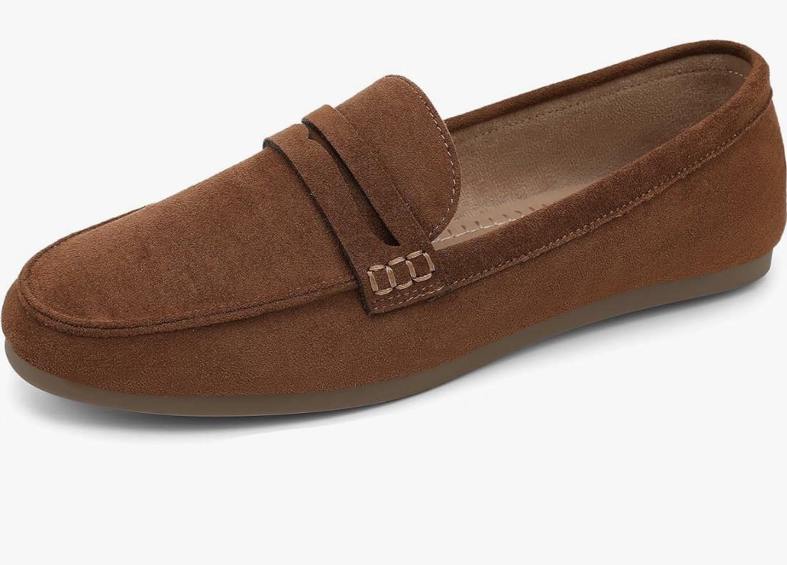 A pair of classic brown suede penny loafers with a traditional strap across the vamp and visible stitching, shown on a transparent background.