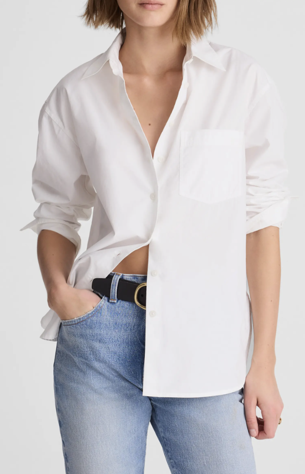 Close-up of a woman wearing an oversized white button-down shirt tucked into light wash cigarette jeans with a black belt.