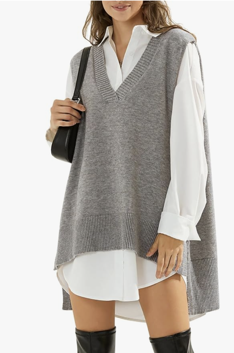 EXLURA oversized grey v-neck sweater vest layered over a white long-sleeve tunic top and paired with black knee-high boots.