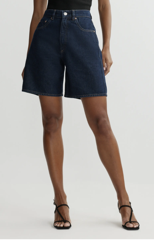 A woman wearing DL1961 Taylor high-waisted denim shorts with a flared A-line hem, designed to add volume and shape to skinny legs.