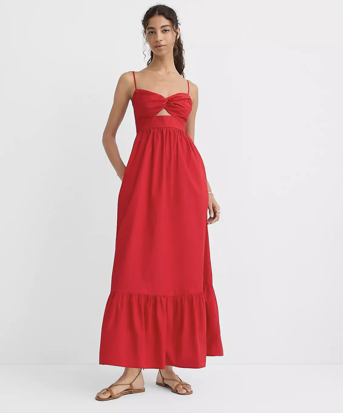 A woman wearing a vibrant red sleeveless maxi dress featuring a sweetheart neckline, front cutout detail, and a tiered skirt.
