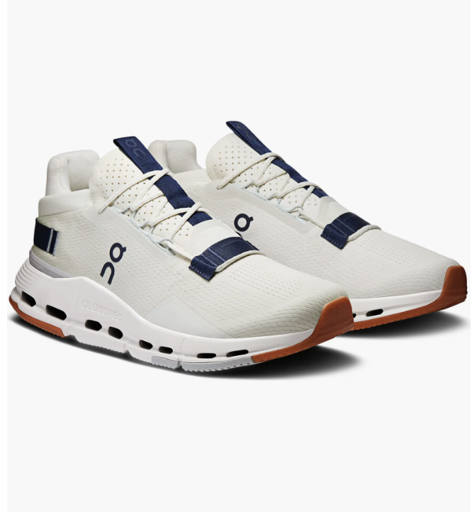 A side profile view of the white On Cloudnova 2 training sneakers, featuring dark navy blue accents and a thick CloudTec cushioned sole.