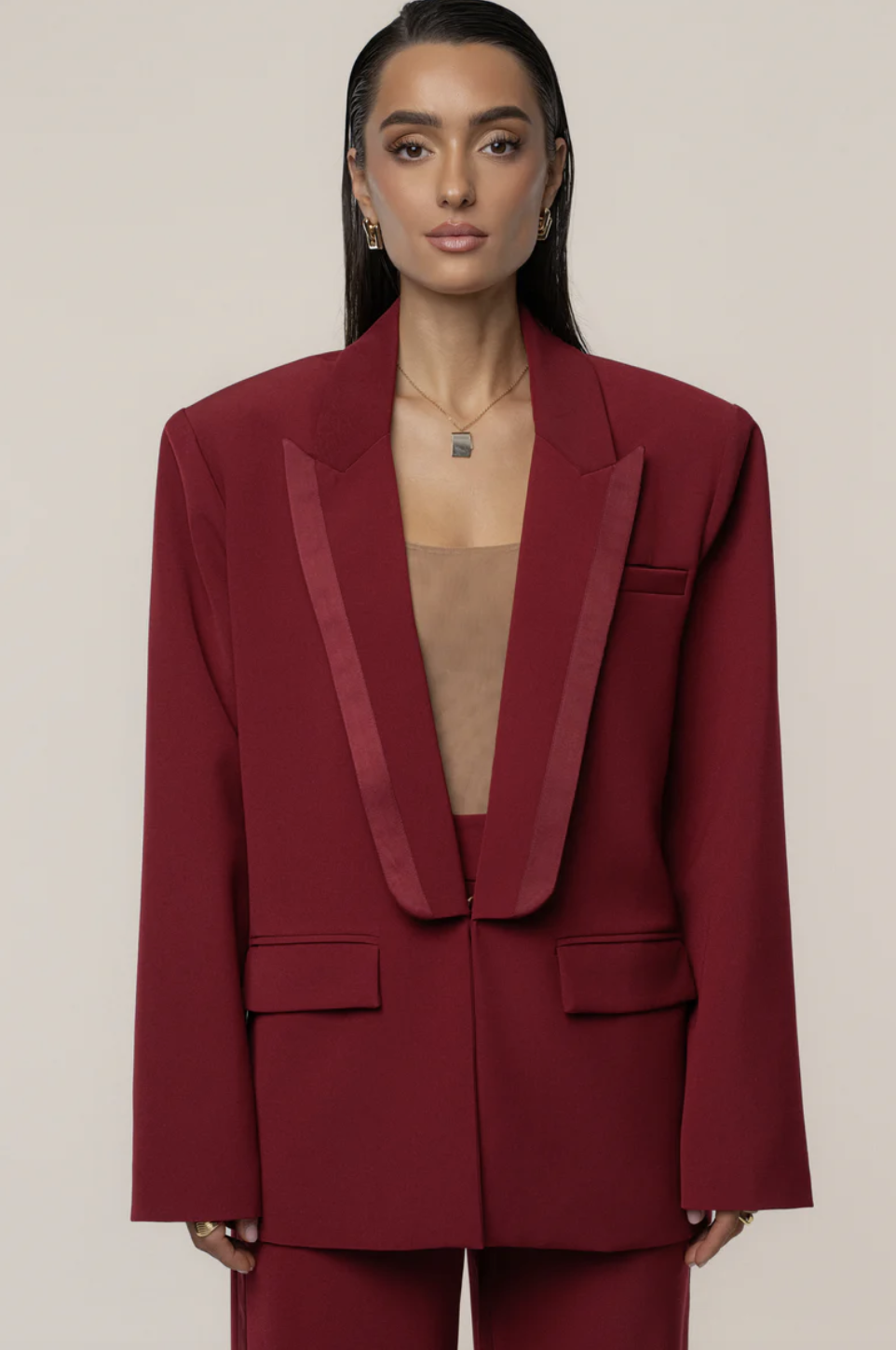 A woman wearing a structured burgundy double-breasted blazer with matching trousers, creating a polished monochromatic power suit.