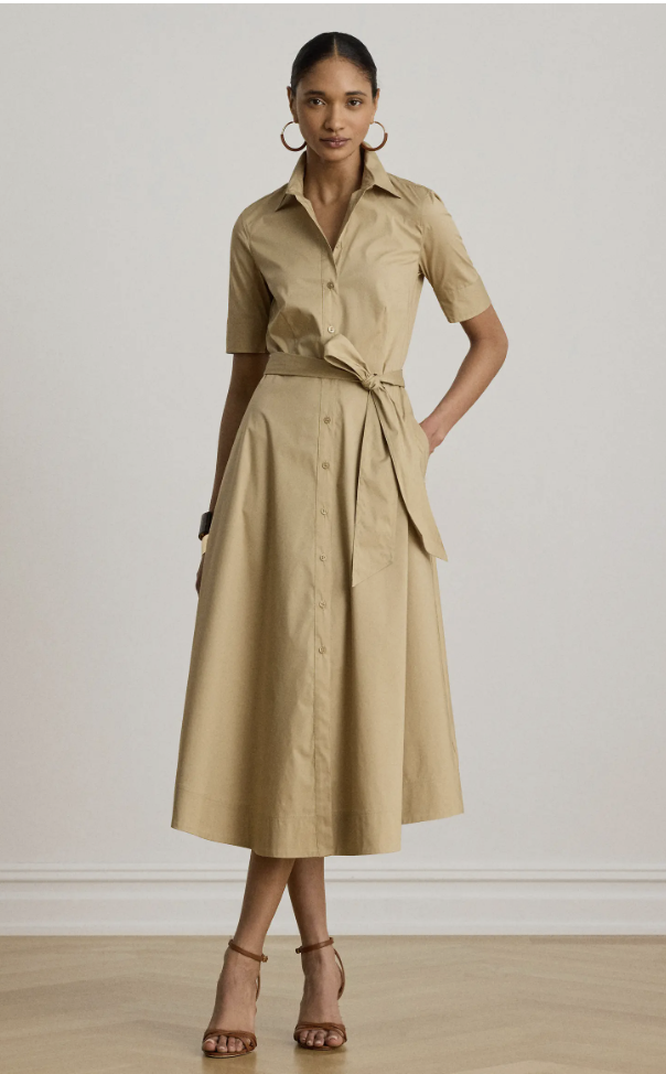 A woman wearing a tan short-sleeve belted utility shirt dress styled with brown strappy heel sandals.