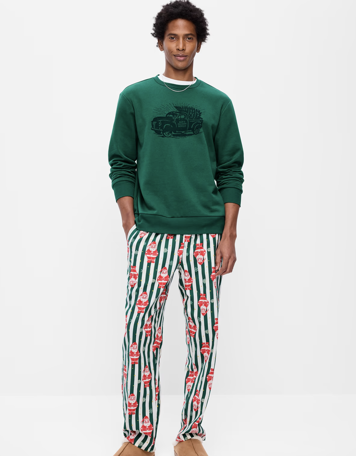 Man wearing Old Navy green and white striped Santa print flannel pajama pants with a green graphic sweatshirt
