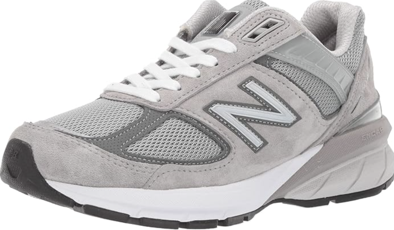 A pair of classic grey New Balance 990v6 sneakers, styled as supportive and professional work sneakers for a casual office environment.
