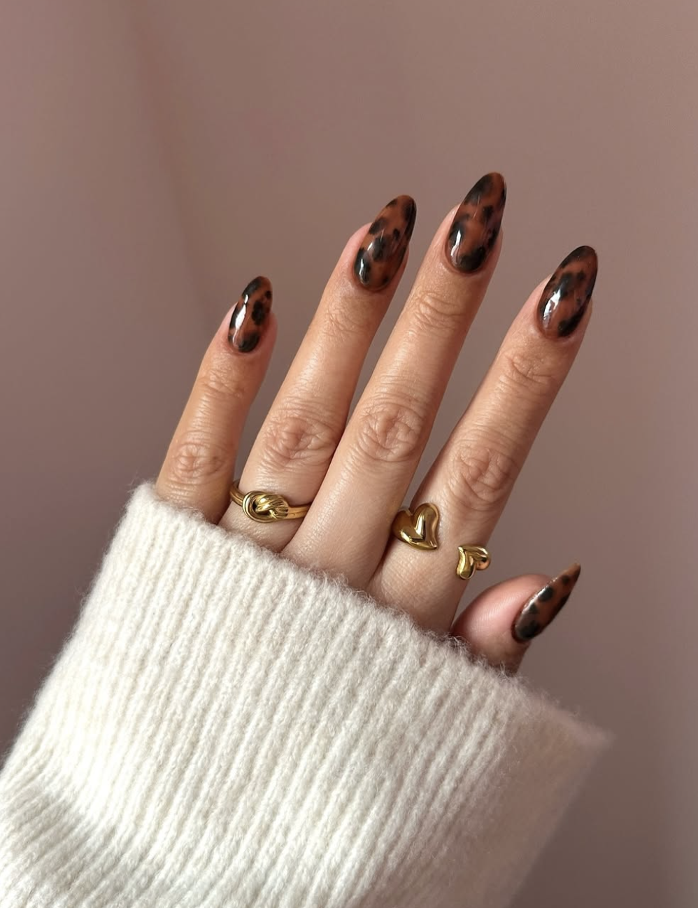 Long almond-shaped gel nails with a multi-dimensional amber and brown tortoiseshell pattern.