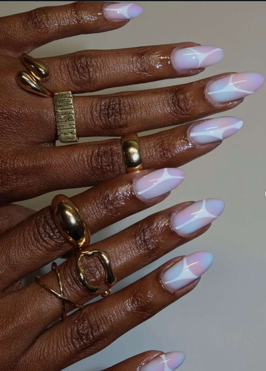 Long, almond-shaped nails featuring a clean, bare base accented by fluid, abstract waves of opaque white and soft lavender-pink polish.