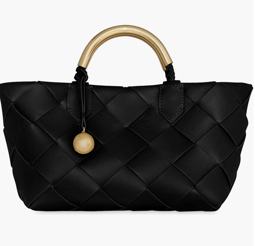 Black woven leather tote bag with a gold ring handle, a textured spring wardrobe essential for 2026.