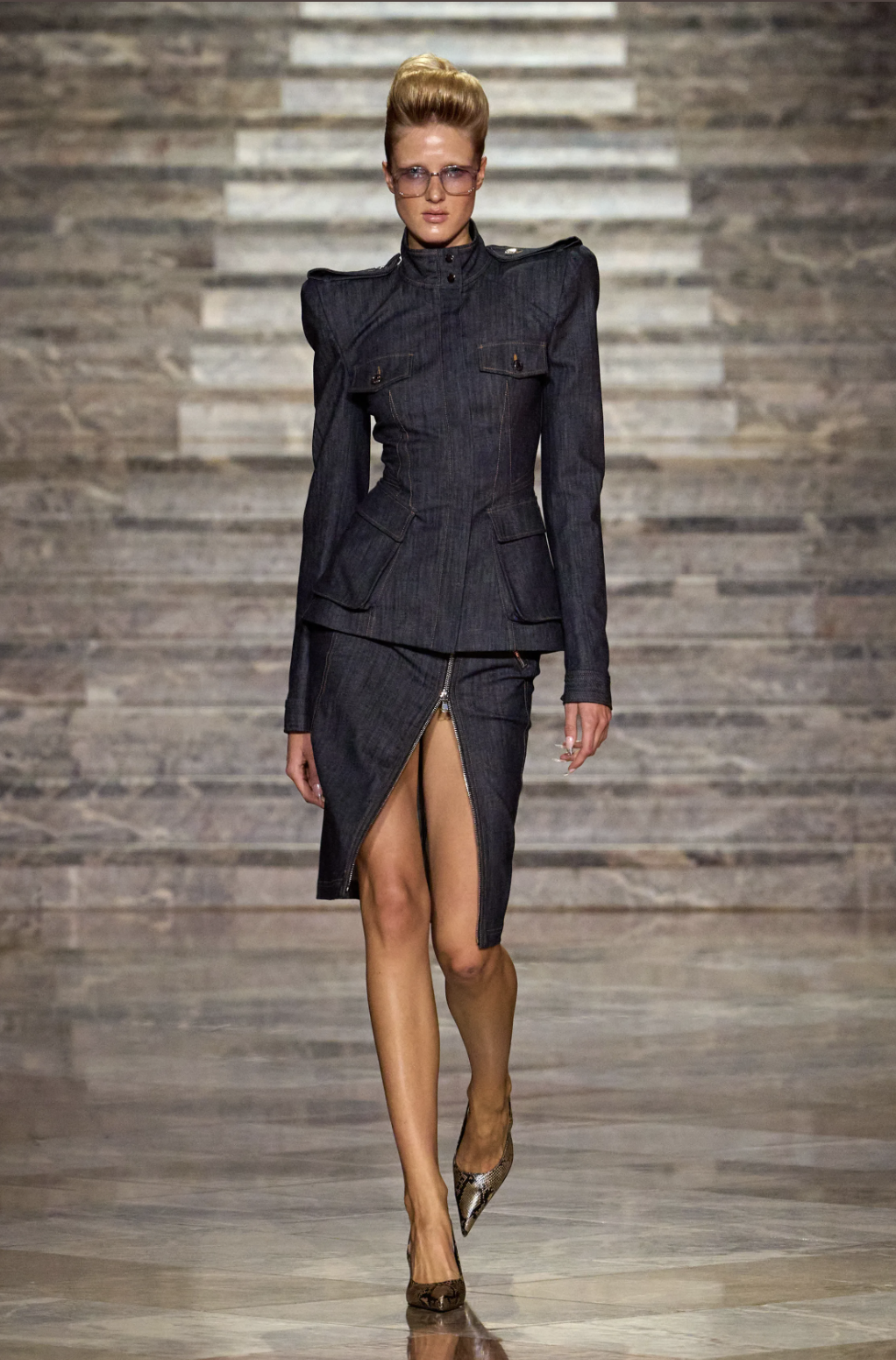 Model in a LaQuan Smith Spring 2027 dark denim jacket with sharp shoulders and a matching skirt with a zip slit