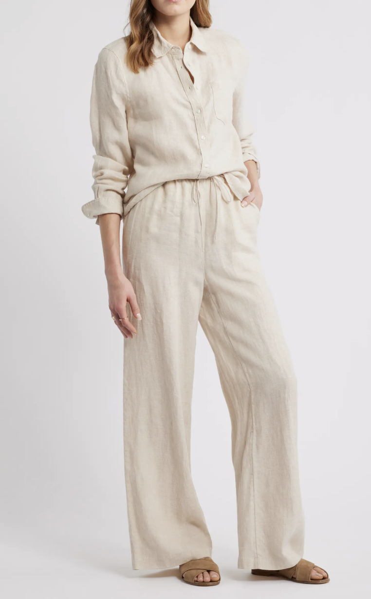 A woman wearing tan wide-leg linen pants with matching sandals, a breathable spring wardrobe essential for 2026.