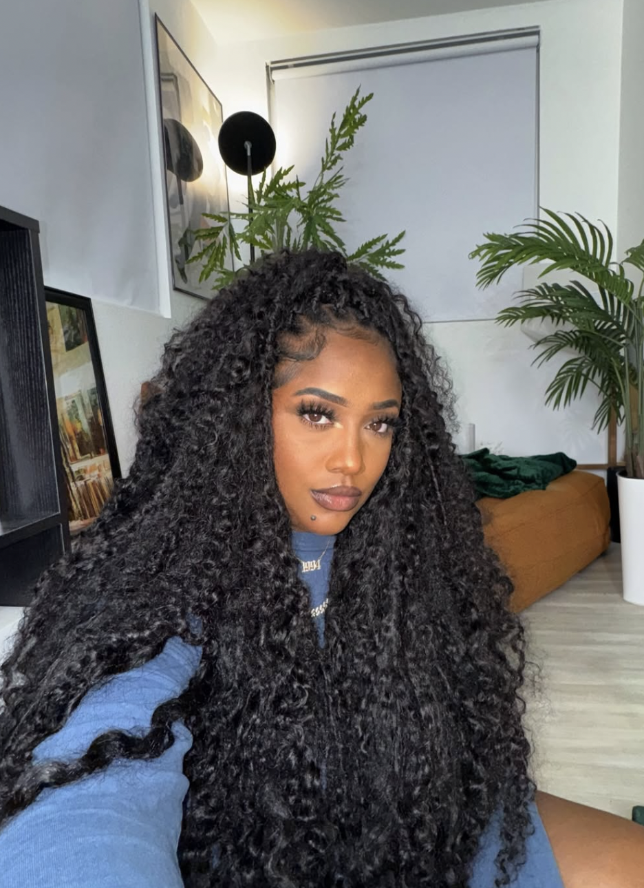 A woman with a square face shape wearing long, textured faux locs swept to the side, showing how the movement and volume of the locs frame a defined jawline.