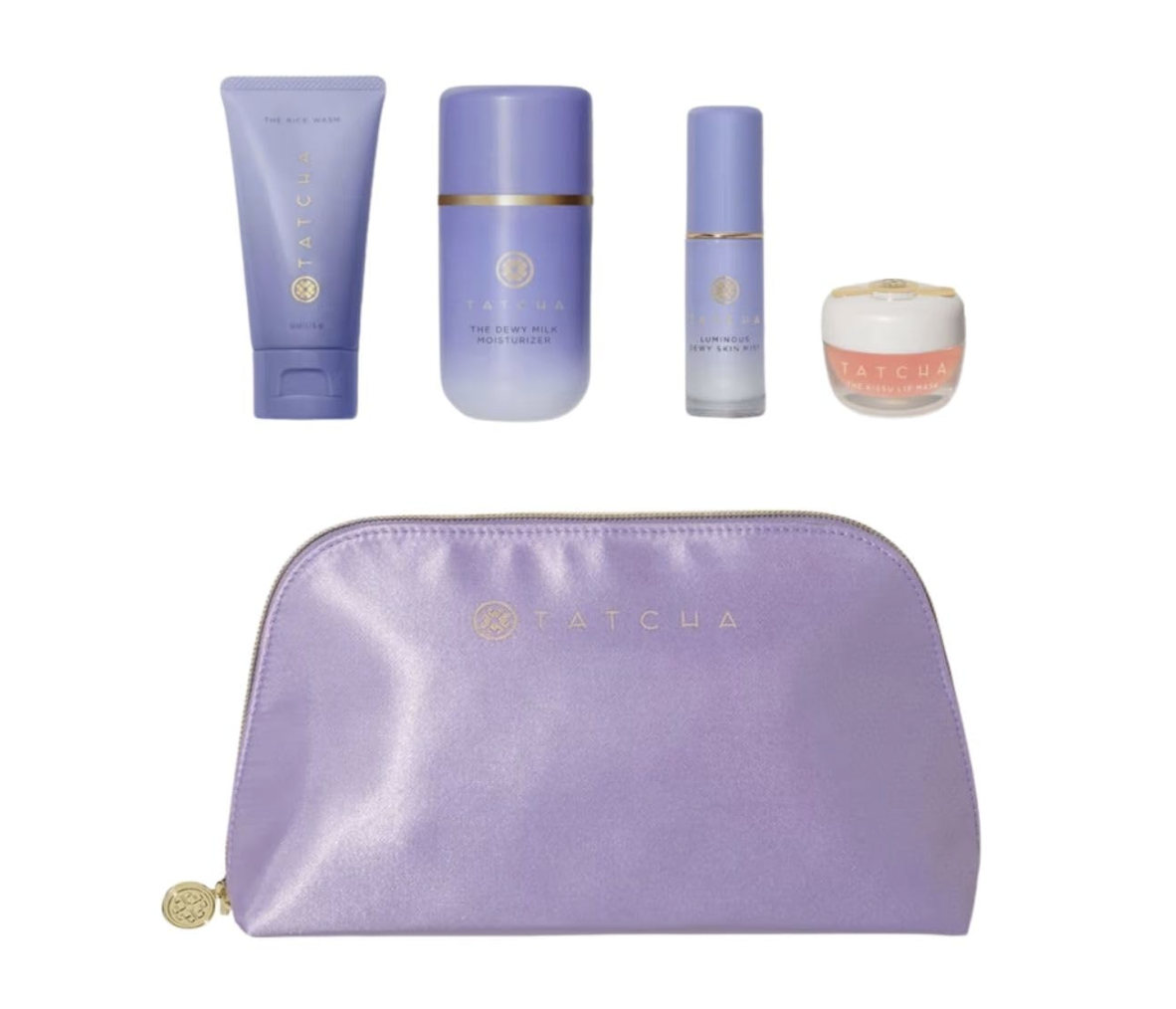 A collection of Tatcha skincare products including a cleanser, essence, and moisturizer next to a lavender purple cosmetic bag.