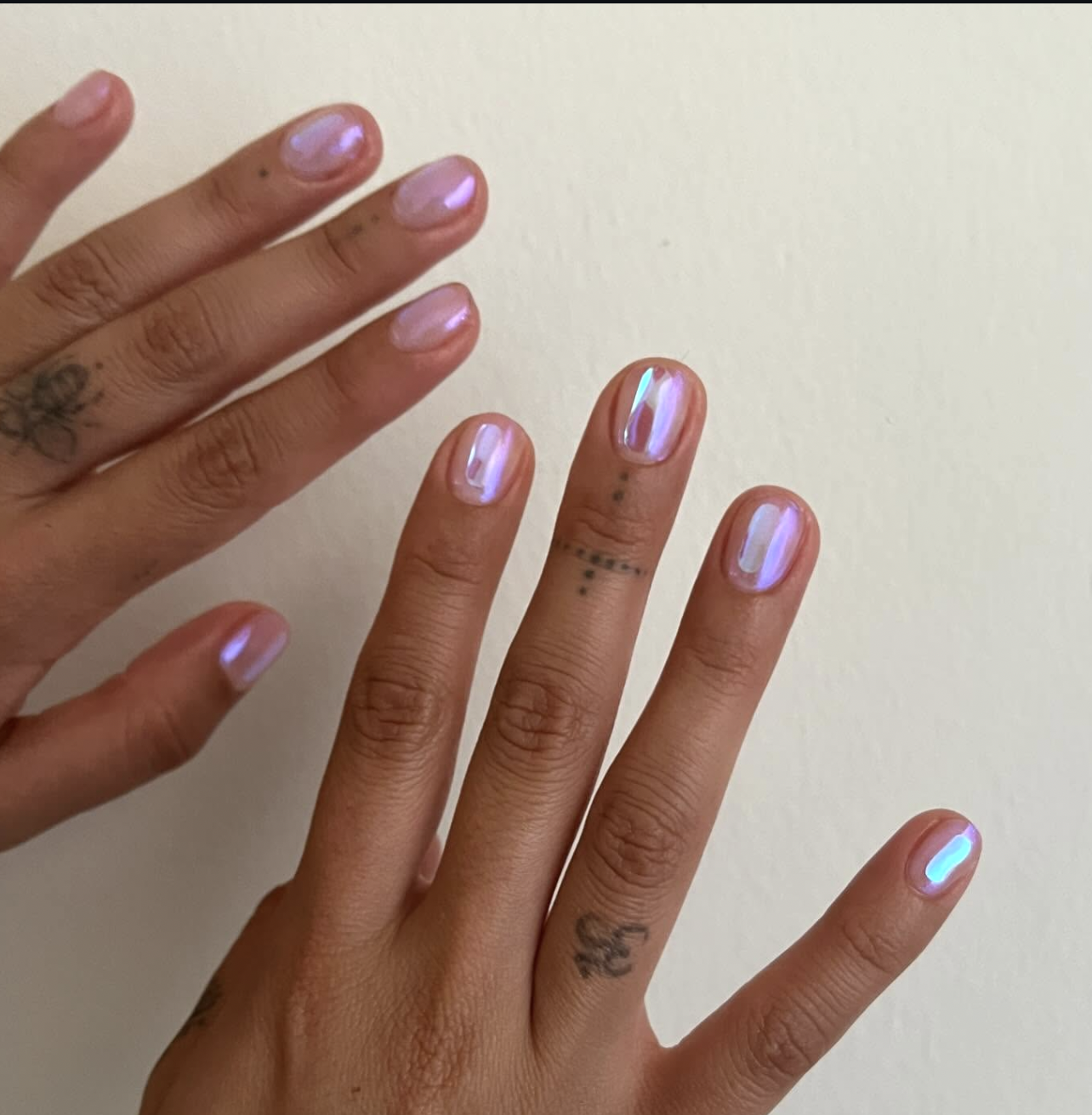Short natural nails featuring a shimmering, iridescent purple chrome finish that catches the light with a metallic glaze.