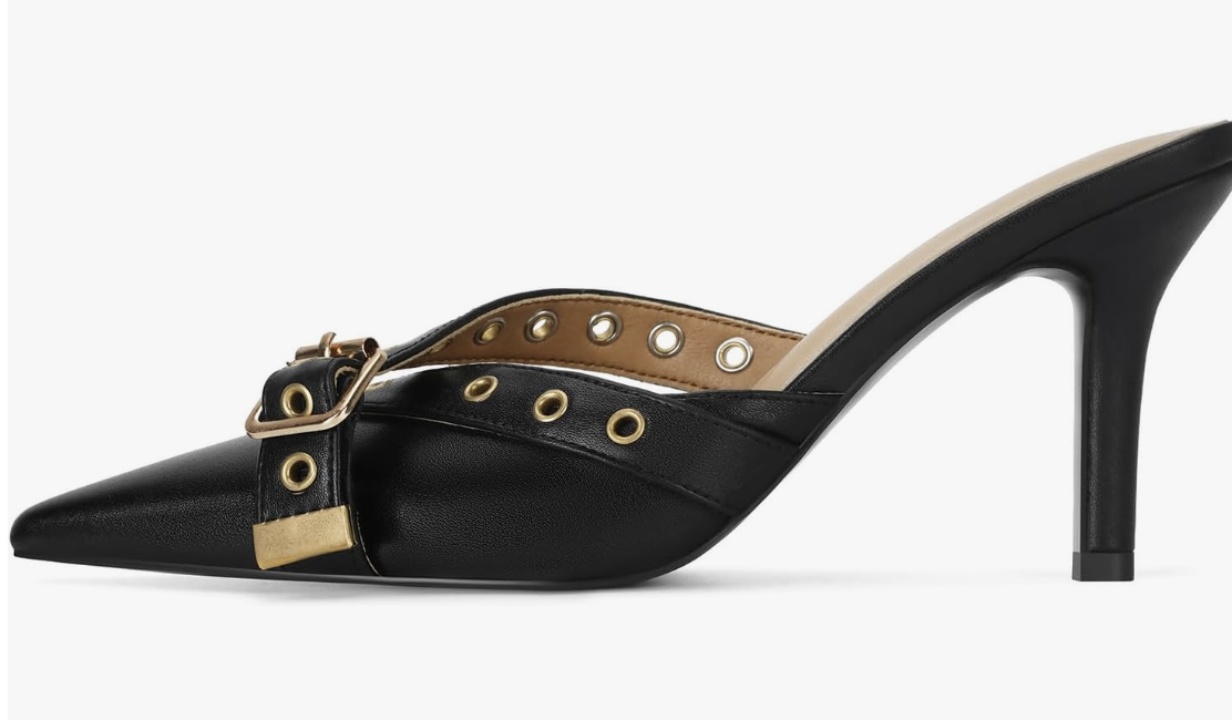 Close-up of a chic black pointed-toe kitten heel featuring edgy silver eyelet straps and a buckle detail.