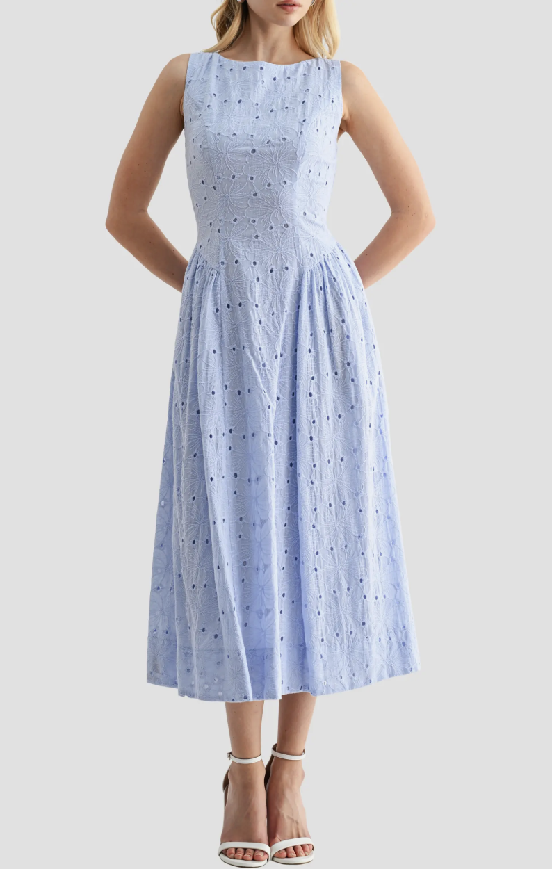 A woman wearing a light blue All in Favor midi dress with sleeveless high neck and intricate eyelet broderie anglaise detailing.
