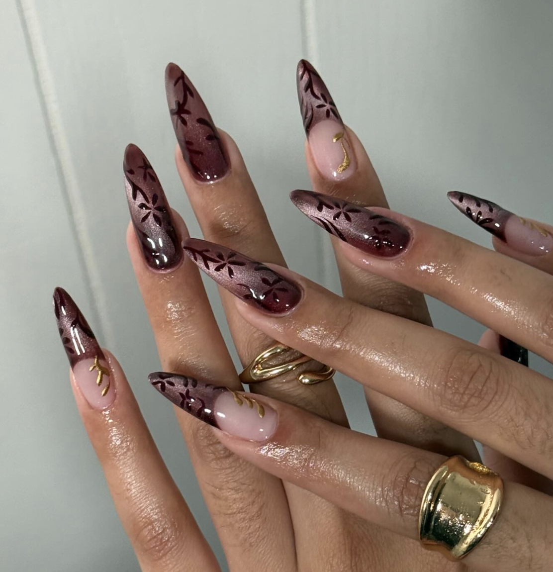 Almond-shaped acrylic nails with a nude base, a single white lace accent nail featuring gold foil and iridescent sparkle, and matching plain nude nails.