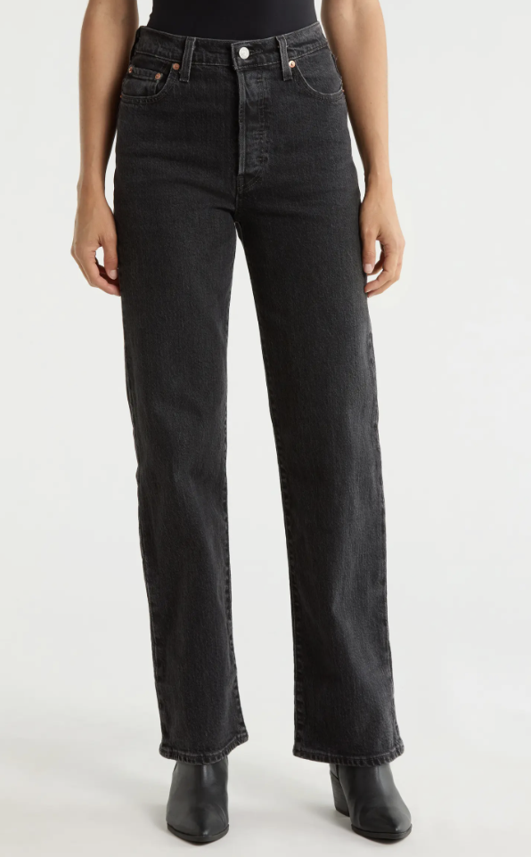 A model wearing high-waisted dark wash straight-leg jeans styled with black pointed leather boots.