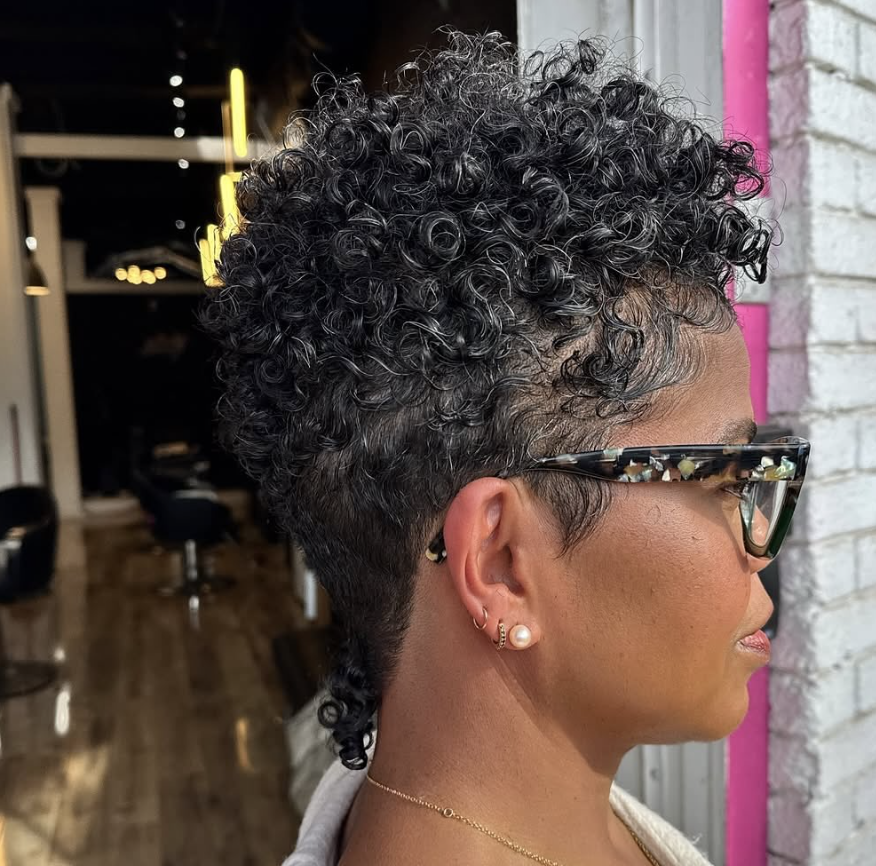 Side view of a woman wearing a tapered curly cut with defined curls and glasses.