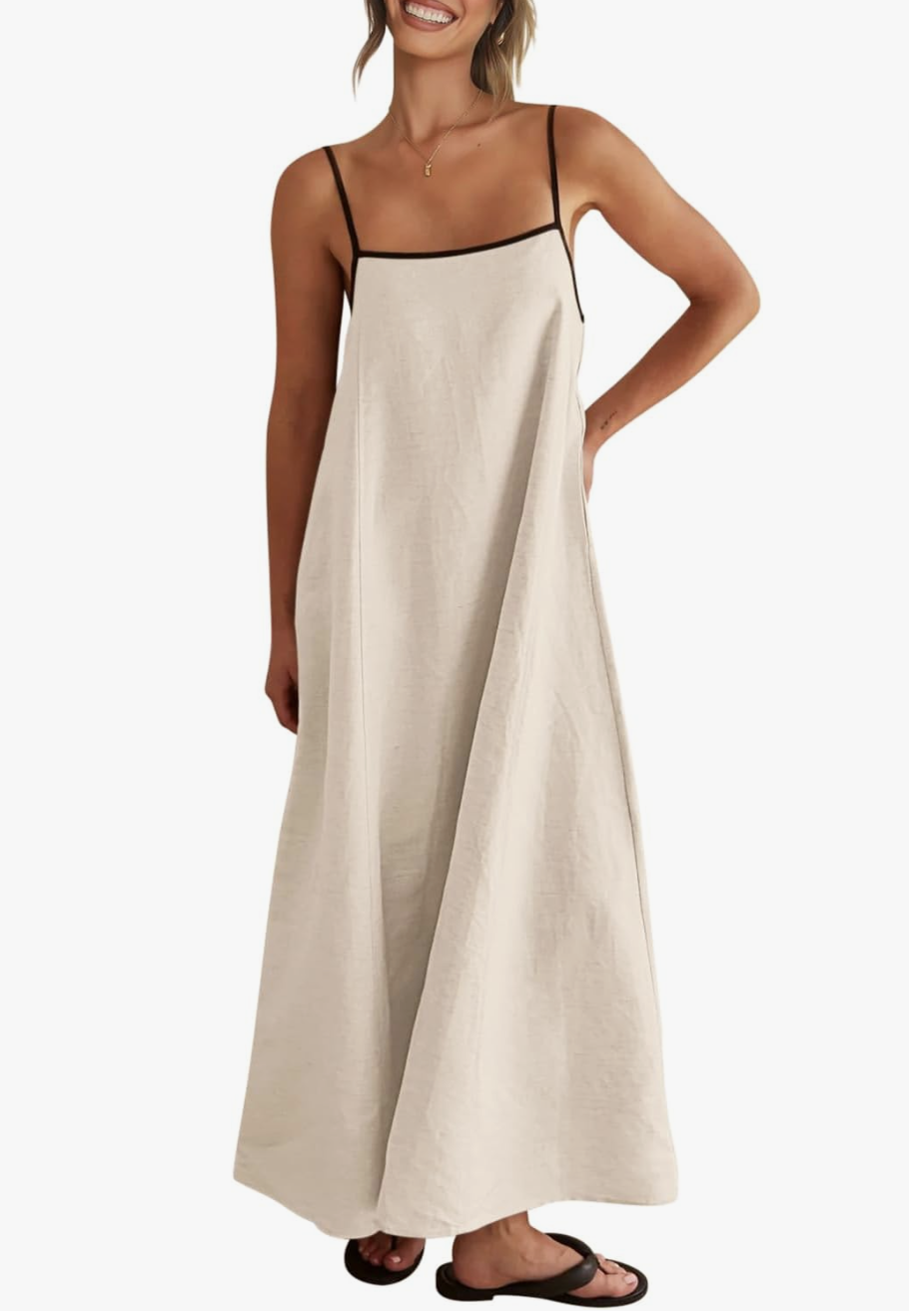 A close-up view of a casual summer outfit featuring a high-waisted, flowy beige linen midi dress with a drawstring waist and side pockets, paired with dark brown flat sandals.