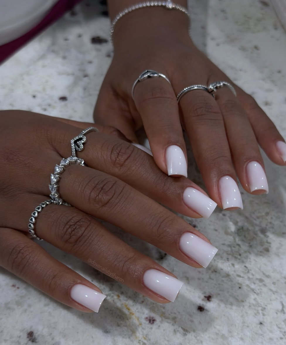 Short squoval nails painted with translucent milky-white polish.