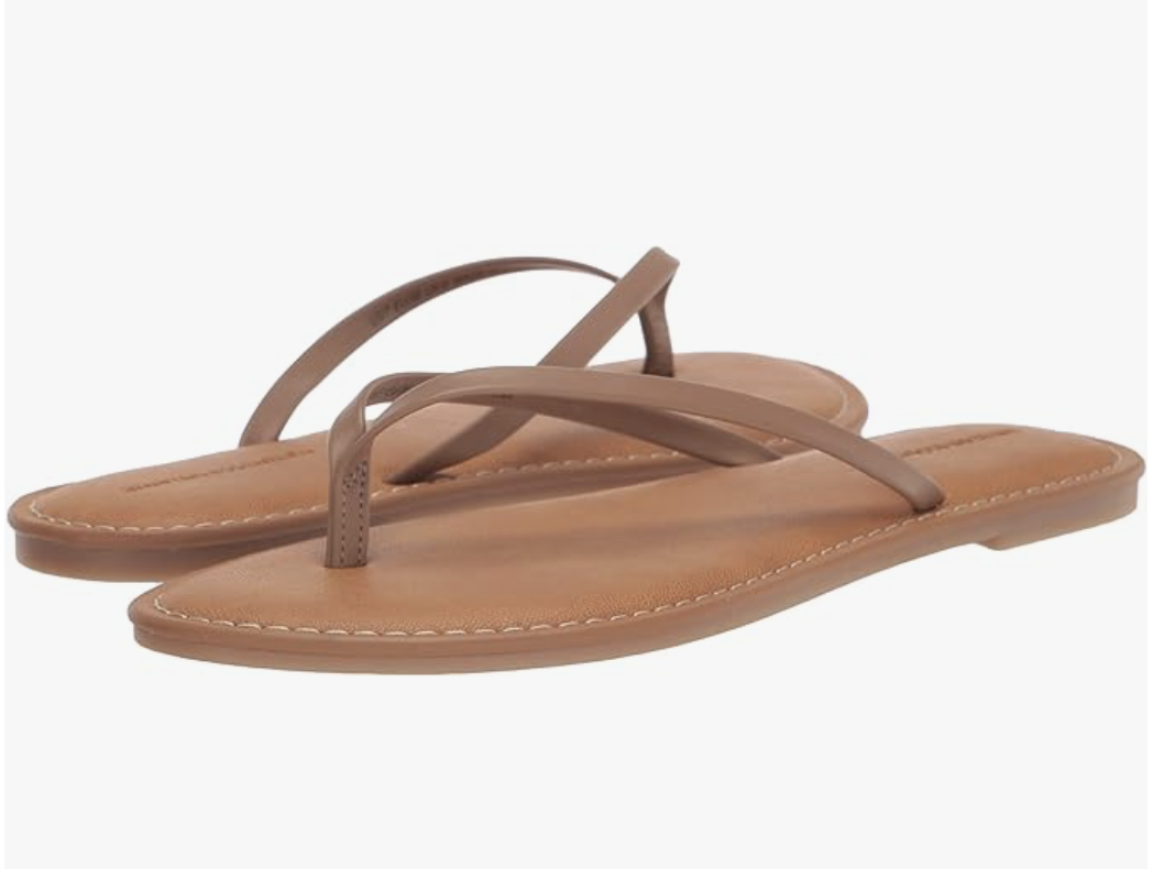 A pair of minimalist black thong sandals with a thin strap and flat sole, styled for a casual summer look.