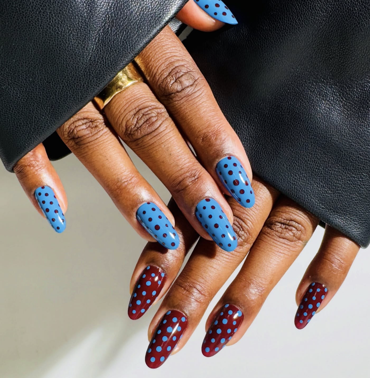Long, oval-shaped nails with a dreamy blueberry milk blue base coat, decorated with a clean pattern of tiny, hand-painted red micro-dots.