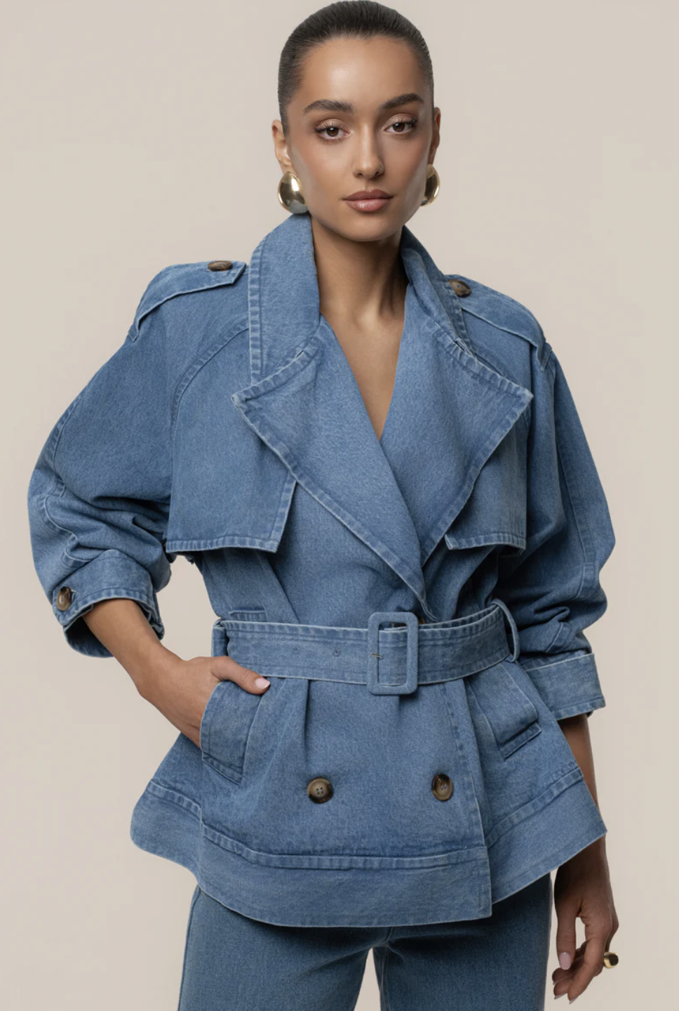 A woman wearing a medium wash double-breasted denim jacket with gold buttons, a structured spring 2026 wardrobe staple.
