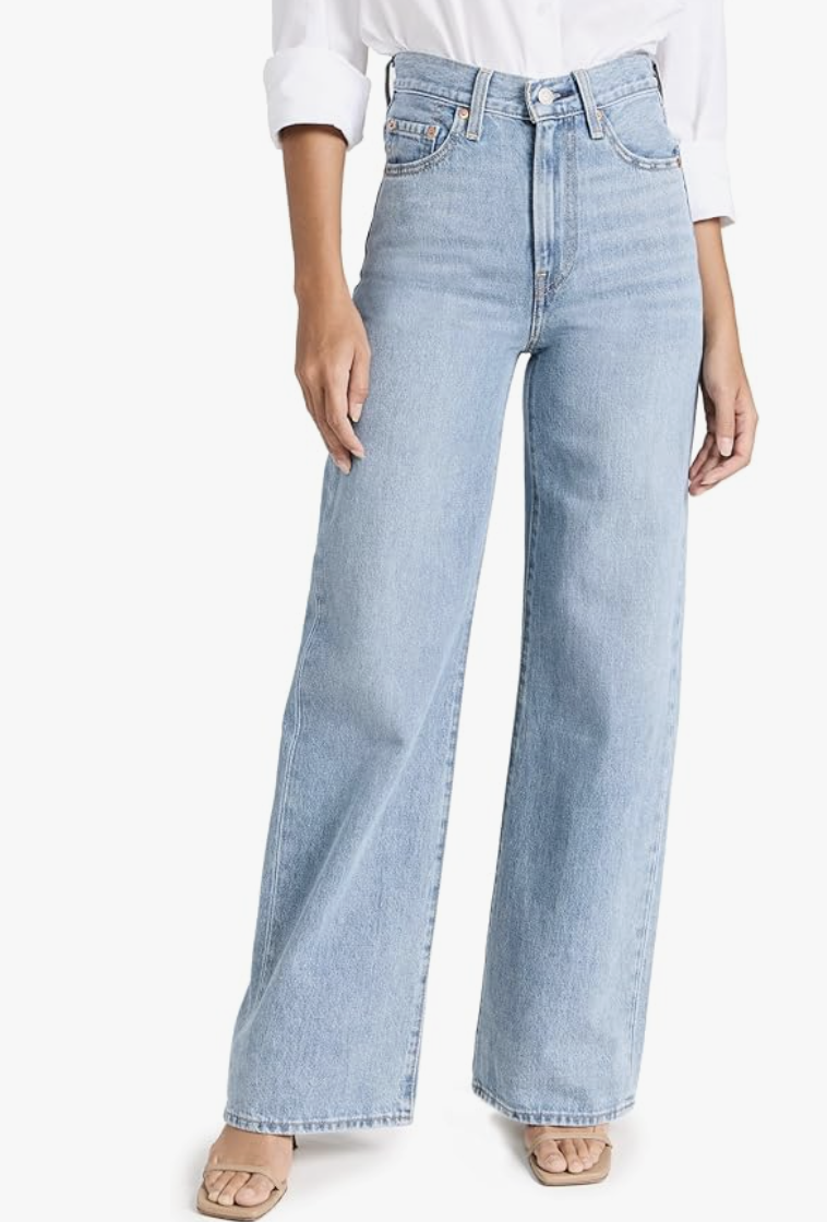 A person with an hourglass figure wearing light wash Levi's Ribcage Straight Ankle jeans, demonstrating how the 12-inch high rise sits at the narrowest part of the waist.