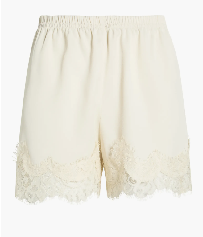 Close-up of ivory satin shorts featuring a delicate eyelash lace trim along the hemline